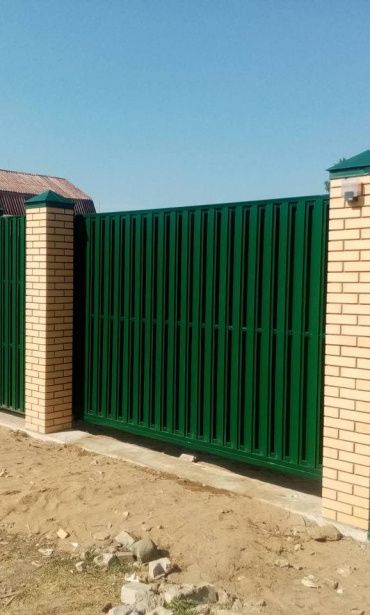 Забор из евроштакетника с кирпичными столбами на прочном фундаменте